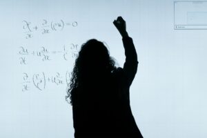 sihoulette of person writing mathematical equations on a whiteboard